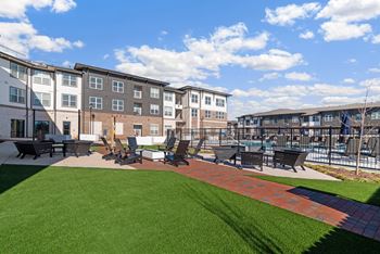 an outdoor lounge area with tables and chairs in front of an apartment building